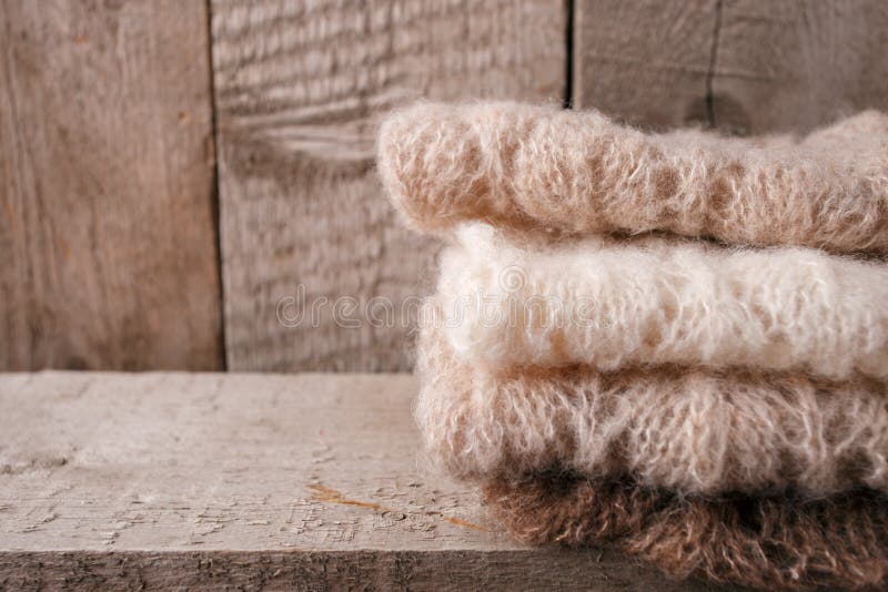 Pila di vestiti dai lavori o indumenti a maglia tricottati su un fondo di legno, spazio della copia Concetto familiare di inverno fotografia stock Pila di vestiti dai lavori o indumenti a maglia tricottati su un fondo di legno, spazio della copia Concetto familiare di inverno fotografia stock