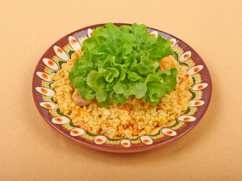 Pilaf dish, bulgur wheat with meat on a ceramic plate with lettuce