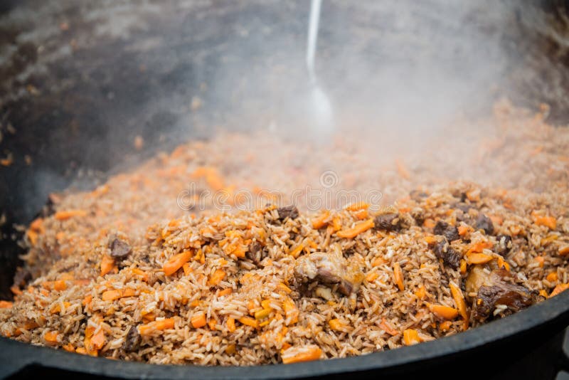 Pilaf savoureux d'Ouzbékistan dans un chaudron sur le feu en plein air au festival de nourriture de rue image libre de droits Pilaf savoureux d'Ouzbékistan dans un chaudron sur le feu en plein air au festival de nourriture de rue image libre de droits