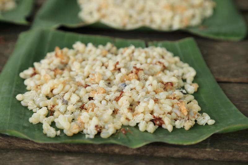 Pile of ant eggs with larva and weaver ants on green banana leaf.