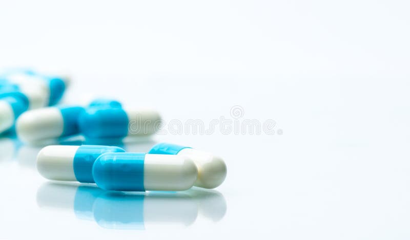 Pile of blue and white capsules pills isolated on white background with shadows and copy space for text.