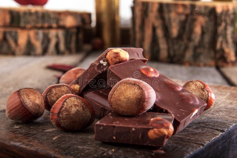 Pile Of Chocolate Pieces With Hazelnuts On Wooden Background Stock