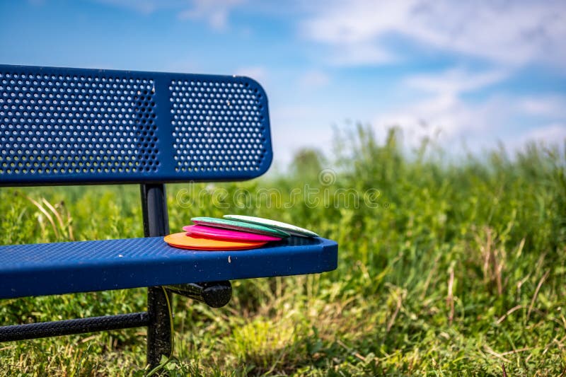 Pile of Discs Resting on a Bench in the Golf Course Park Stock Image