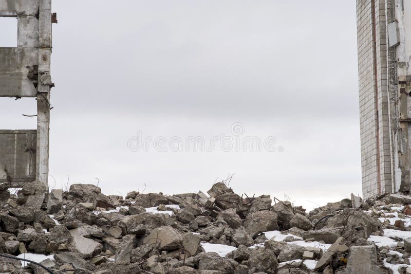 A pile of large gray concrete fragments with protruding fittings against a cloudy sky