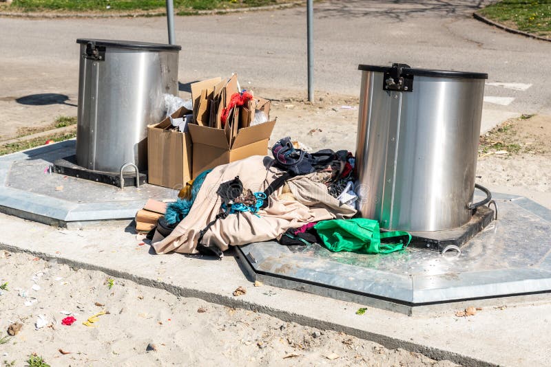 Pile of old clothes and shoes dumped on the underground dumpster cans as junk and garbage, littering and polluting the urban city royalty free stock photography
