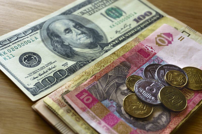 Ukrainian metal coins of 1, 2 hryvnias stacked against 100 American dollars, reduction of the hryvnias and the dollar stock images Ukrainian metal coins of 1, 2 hryvnias stacked against 100 American dollars, reduction of the hryvnias and the dollar stock images