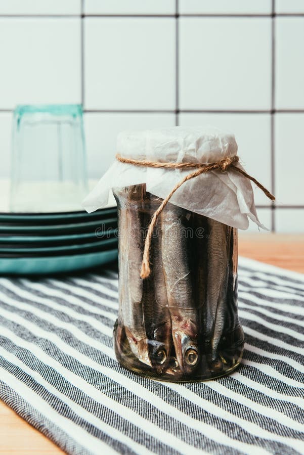 Pile of salted fish in jar wrapped by string on towel with plates