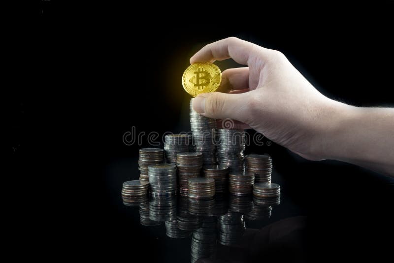 Pile of stacking coins with shiny golden bitcoin on top with grabbing hand, king of all coins, most valuable coin, rising royalty free stock image
