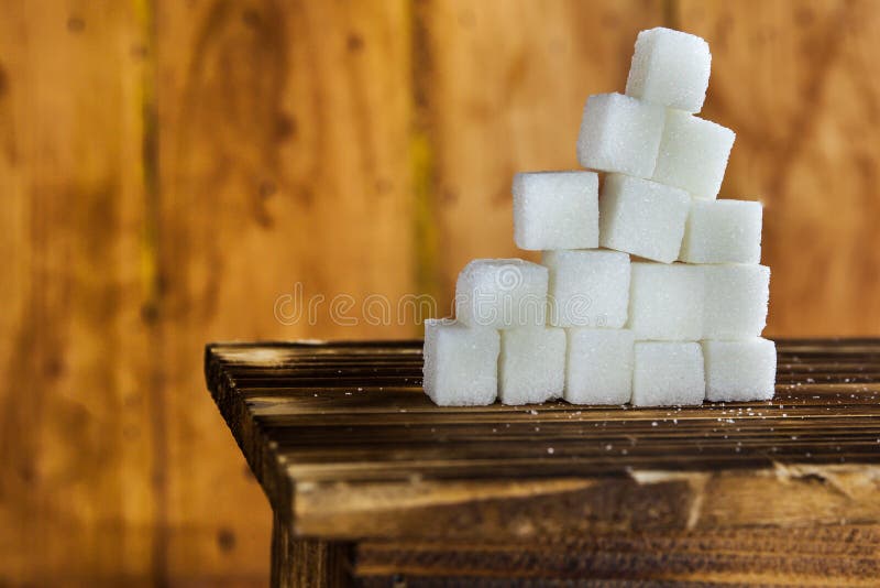 Pile of Sugar Cubes Stacking on Table over Wooden Background. stock photo