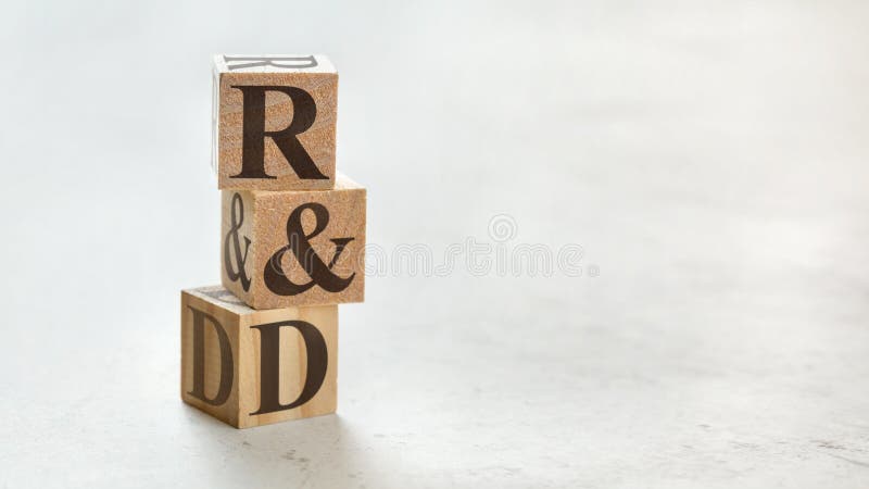 Pile with three wooden cubes - letters R&D meaning Research and Development on them, space for more text / images at right side
