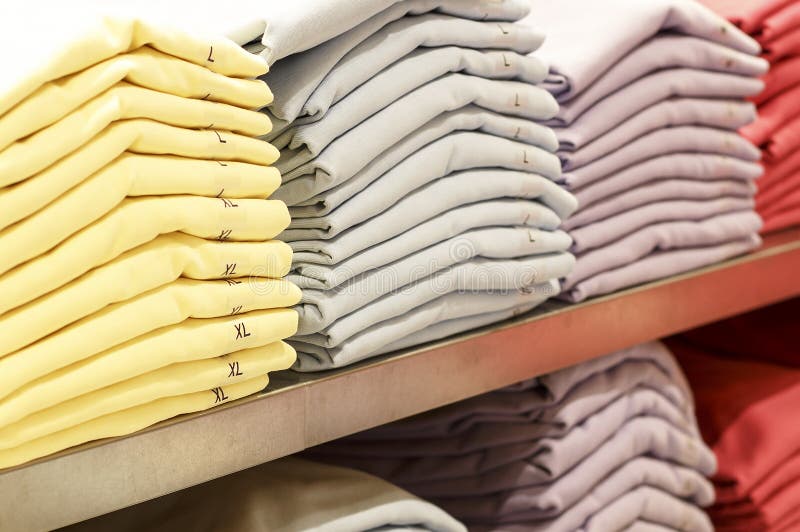Piles des vêtements multicolores sur les étagères dans le magasin images libres de droits Piles des vêtements multicolores sur les étagères dans le magasin images libres de droits