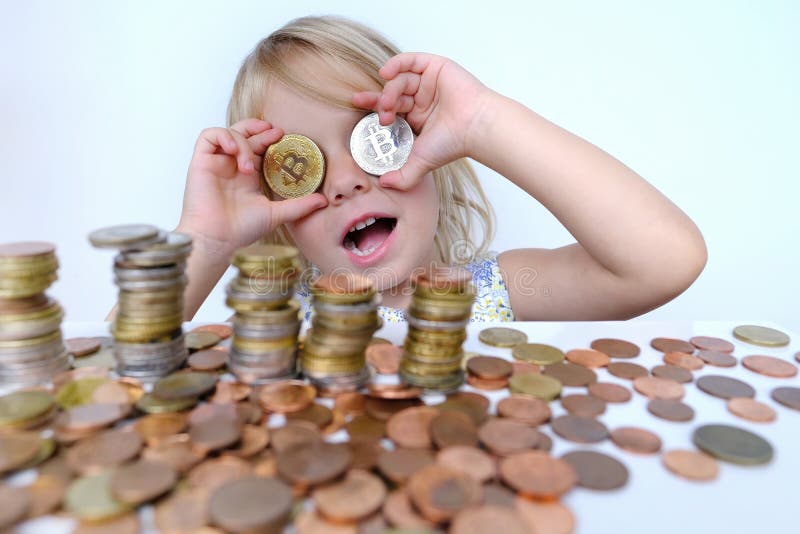 Stacks of euro currency coins, small child, blonde girl 3 years old holds bitcoin crypto currency coins in hands, financial literacy of children, Electronic decentralized money, bitcoin glasses. Stacks of euro currency coins, small child, blonde girl 3 years old holds bitcoin crypto currency coins in hands, financial literacy of children, Electronic decentralized money, bitcoin glasses