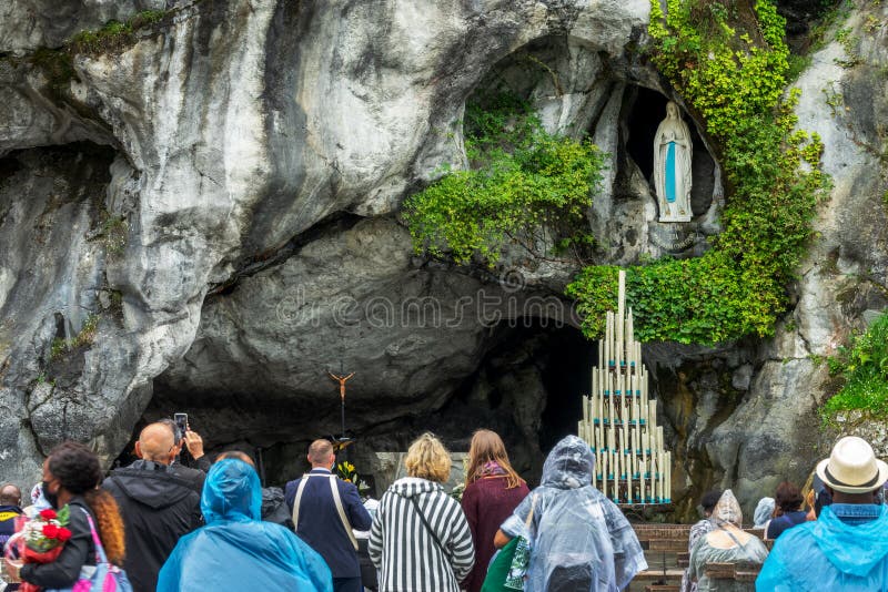 Pilgrims praying the statue of Virgin Mary in the grotto of Our Lady of Lourdes, France