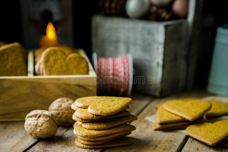 Pilha das cookies cozidas home do pão-de-espécie do Natal na caixa de madeira, vela ardente, fita vermelha e branca, cones do pin fotografia de stock royalty free Pilha das cookies cozidas home do pão-de-espécie do Natal na caixa de madeira, vela ardente, fita vermelha e branca, cones do pin fotografia de stock royalty free