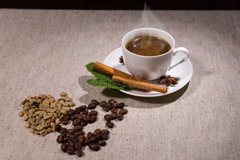 Pilha de feijões e de ervas de java com café quente imagens de stock Pilha de feijões e de ervas de java com café quente imagens de stock