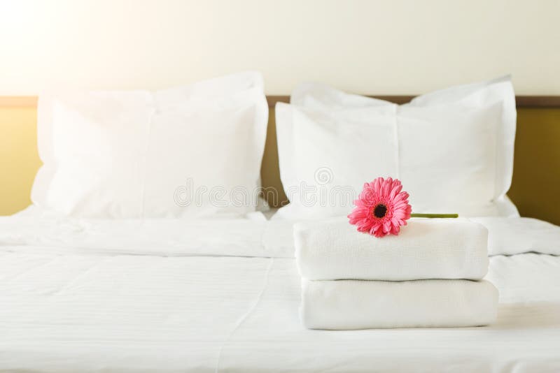 Pilha de toalhas e de flor na cama na sala de hotel imagem de stock royalty free Pilha de toalhas e de flor na cama na sala de hotel imagem de stock royalty free