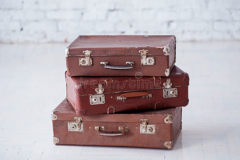 Stack of three brown retro suitcases on white floor. Stack of three brown retro suitcases on white floor.