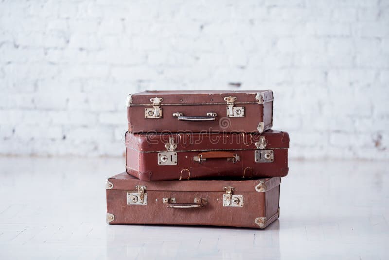 Stack of three brown retro suitcases on white floor. Stack of three brown retro suitcases on white floor.