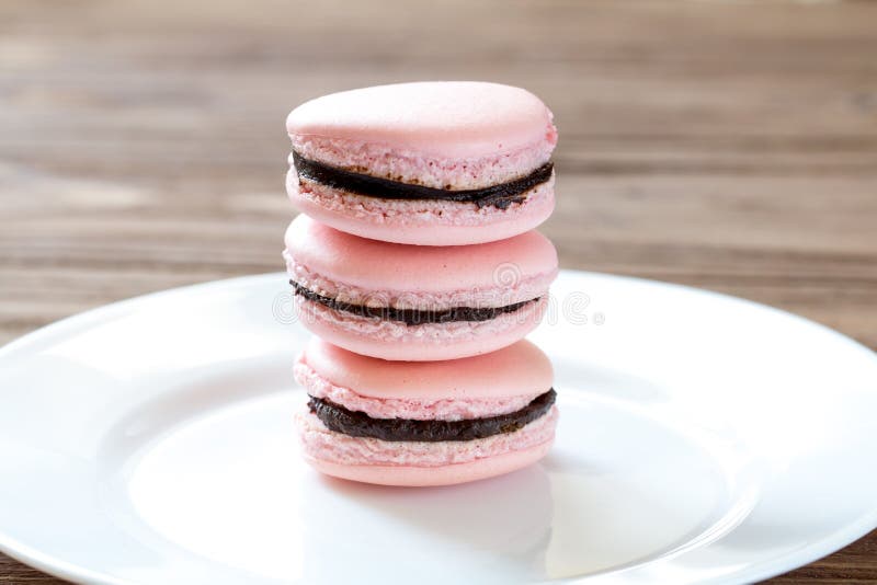 A pilha do macaron do rosa do deserto de três franceses endurece na placa branca fotografia de stock A pilha do macaron do rosa do deserto de três franceses endurece na placa branca fotografia de stock