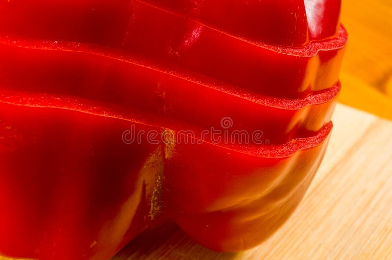 Pilha empilhada da paprika vermelha fresca cortada, pimenta de sino na placa de corte de bambu imagem de stock