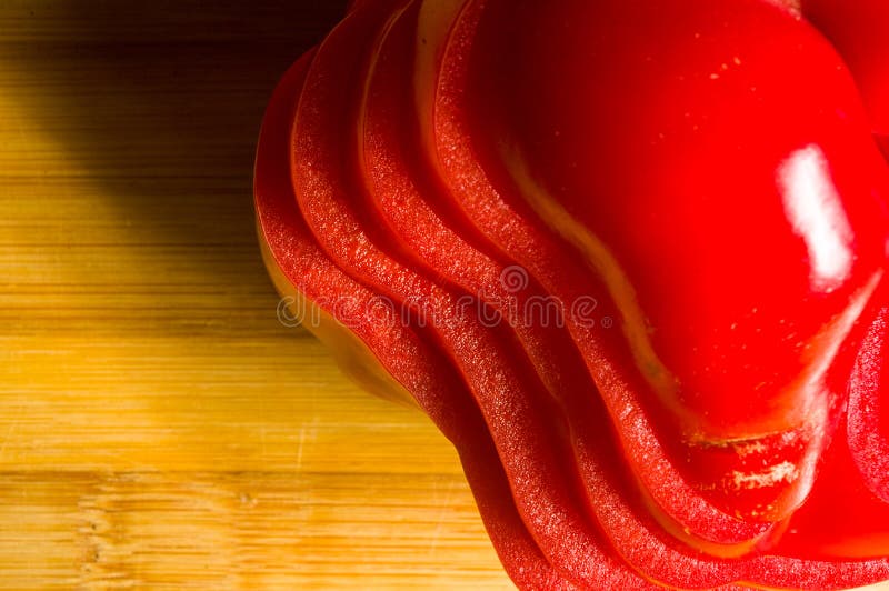 Pilha empilhada da paprika vermelha fresca cortada, pimenta de sino na placa de corte de bambu fotografia de stock