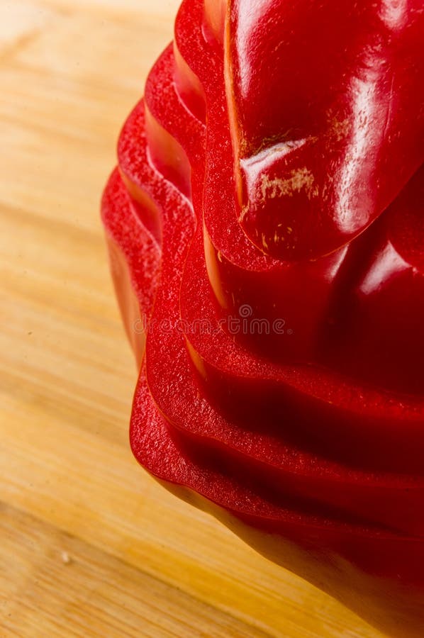 Pilha empilhada da paprika vermelha fresca cortada, pimenta de sino na placa de corte de bambu foto de stock
