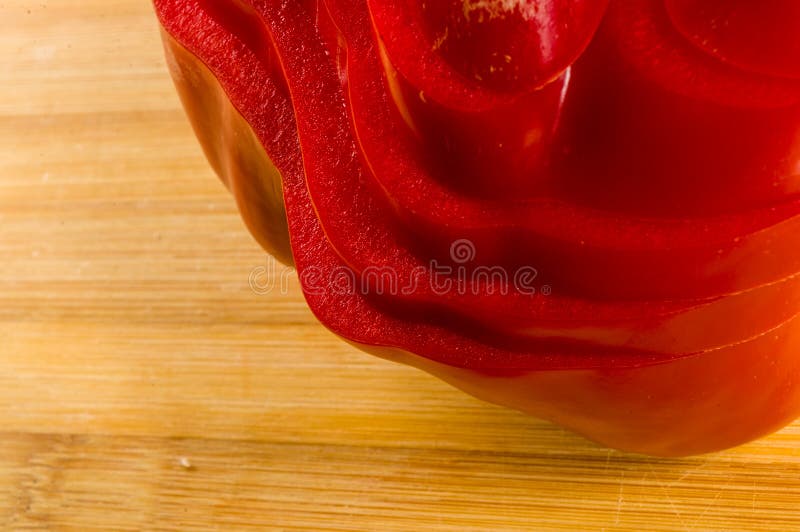 Pilha empilhada da paprika vermelha fresca cortada, pimenta de sino na placa de corte de bambu imagem de stock
