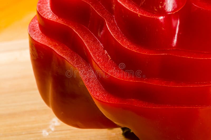 Pilha empilhada da paprika vermelha fresca cortada, pimenta de sino na placa de corte de bambu fotografia de stock