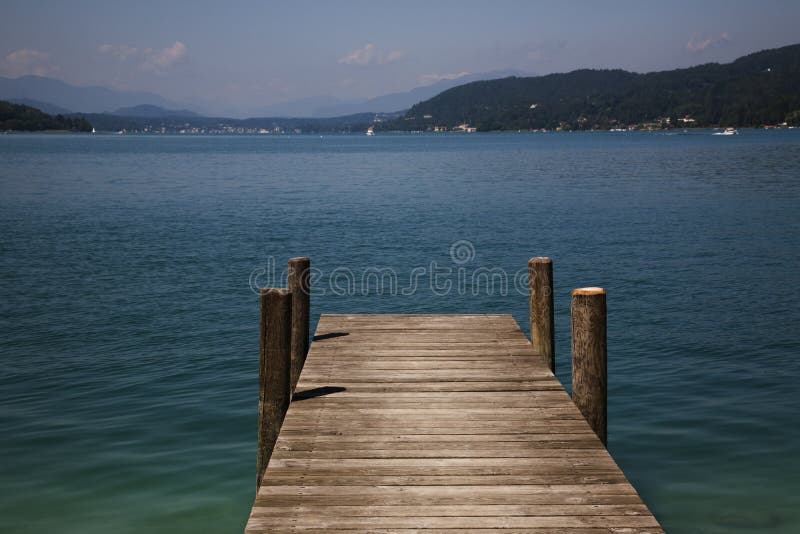 Scenic view of wooden pier on lake with mountains in background. Scenic view of wooden pier on lake with mountains in background.