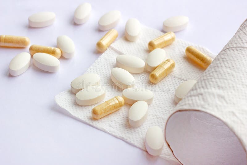 Piller, kapslar och minnestavlor med toalettpapper på ljus bakgrund Apotek och medicin för diarré- och förstoppningbegrepp arkivfoton Piller, kapslar och minnestavlor med toalettpapper på ljus bakgrund Apotek och medicin för diarré- och förstoppningbegrepp arkivfoton