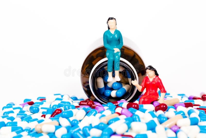 Pillole che versano dalla bottiglia marrone con la gente miniatura fotografia stock libera da diritti Pillole che versano dalla bottiglia marrone con la gente miniatura fotografia stock libera da diritti