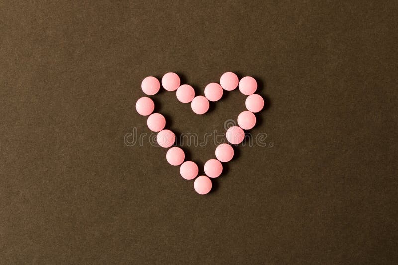 Pillole in forma di cuore su un fondo scuro La vista dalla parte superiore