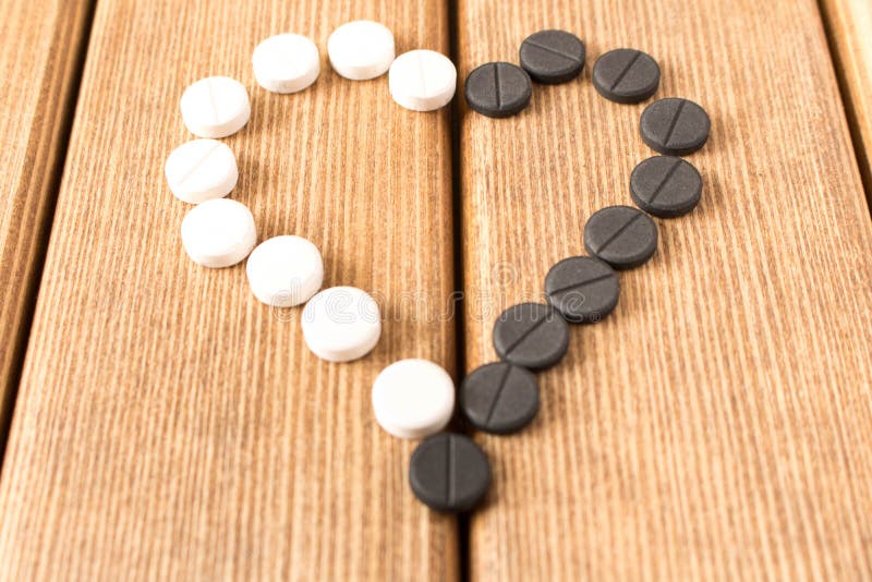 Pillole in forma di cuore su una tavola di legno