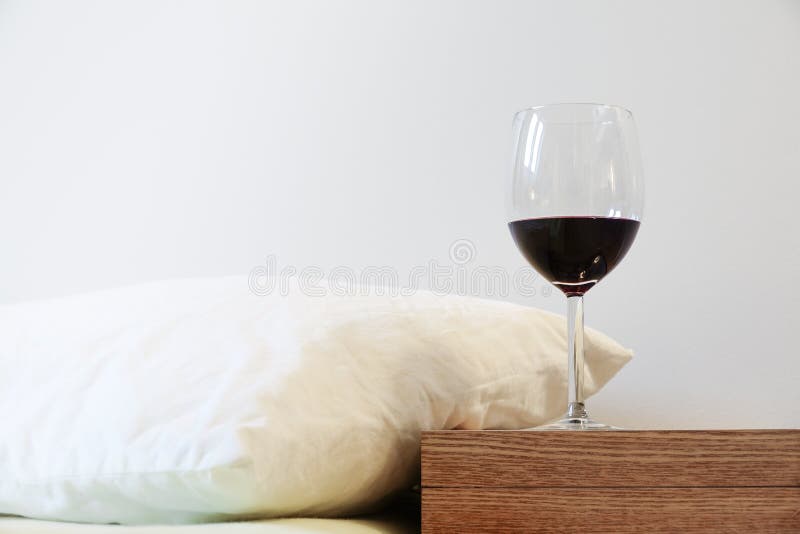 Pillow and Wine Glass on Bedside Table. Concept of Alcohol Drinking