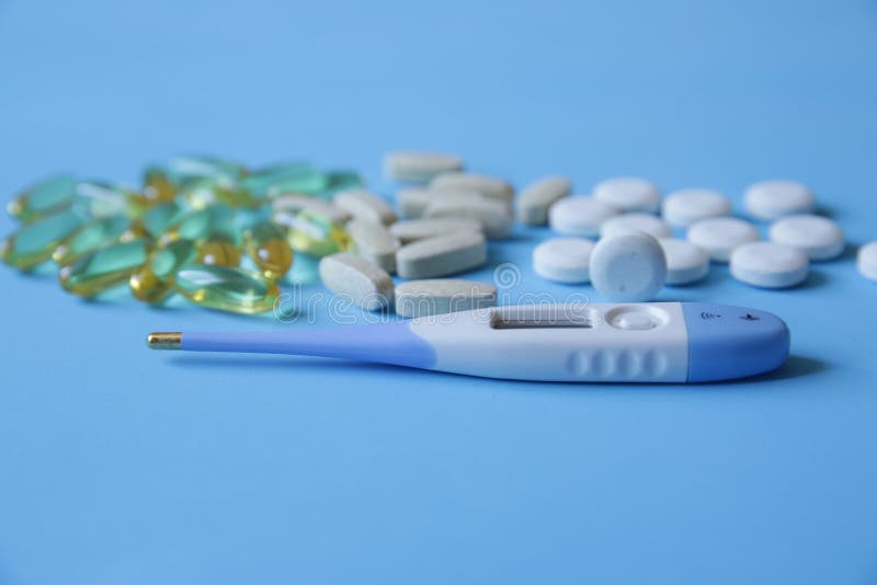 Pills, Capsules and a Thermometer for Measuring Body Temperature on a
