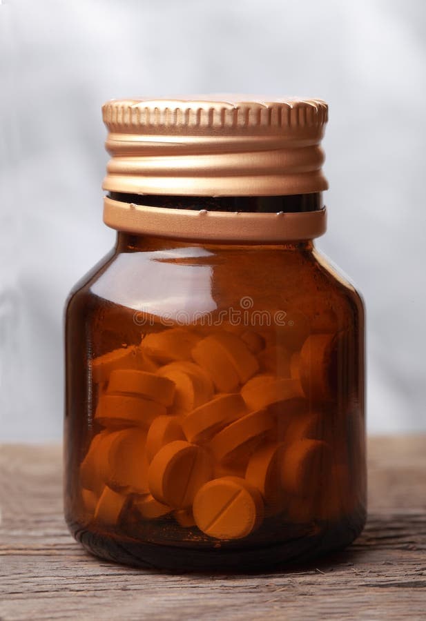 Pills in a opened glass vial royalty free stock photo