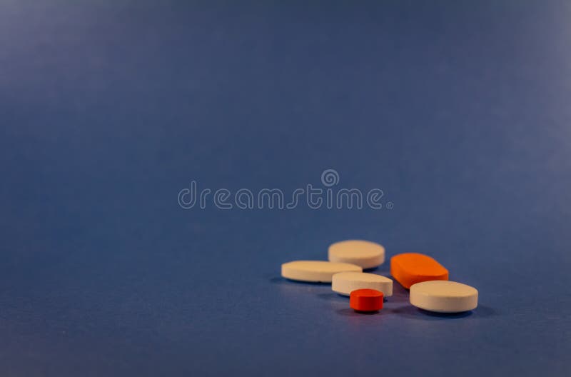 Pills of various colors on a neutral blue background