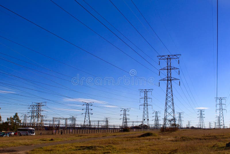 Pilones de la electricidad contra el cielo azul en el terreno desigual foto de archivo libre de regalías Pilones de la electricidad contra el cielo azul en el terreno desigual foto de archivo libre de regalías