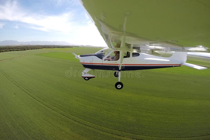 Pilot in einem Flugzeug, das über grüne Felder fliegt stockfotos