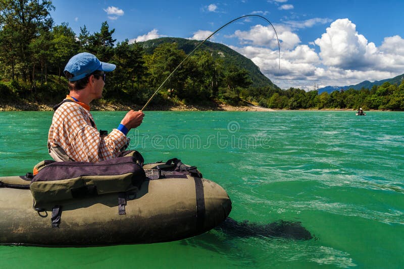 Piloti il pescatore su combattimento del bellyboat con la grande trota, Slovenia fotografia stock Piloti il pescatore su combattimento del bellyboat con la grande trota, Slovenia fotografia stock
