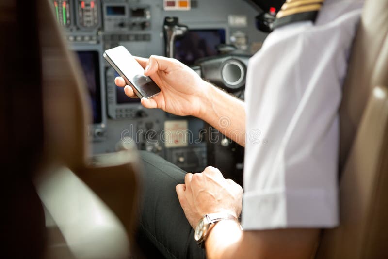 Piloto Using Cell Phone na cabina do piloto fotografia de stock royalty free Piloto Using Cell Phone na cabina do piloto fotografia de stock royalty free