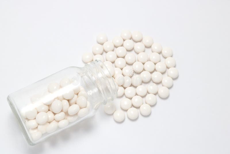Pilules blanches se renversant hors d'une bouteille transparente de médecine images libres de droits Pilules blanches se renversant hors d'une bouteille transparente de médecine images libres de droits