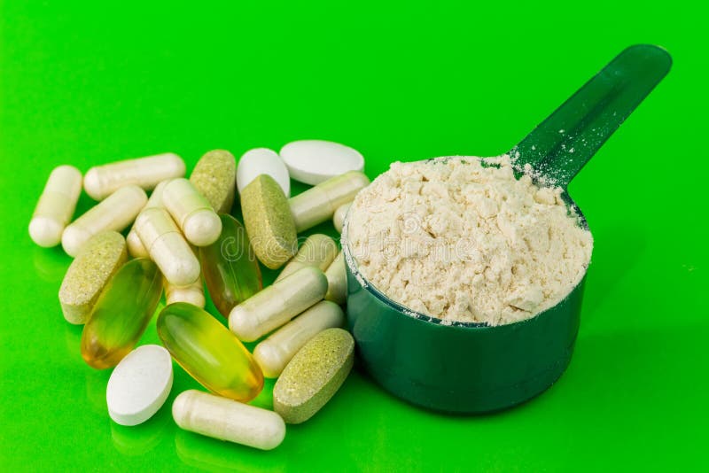 Pilules de complément alimentaire et poudre naturelles mélangées de protéine dans la cuillère en plastique sur le fond vert photographie stock libre de droits Pilules de complément alimentaire et poudre naturelles mélangées de protéine dans la cuillère en plastique sur le fond vert photographie stock libre de droits