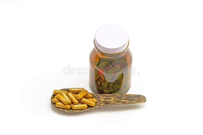 Pilules jaunes dans la cuillère et la bouteille en bois photo stock Pilules jaunes dans la cuillère et la bouteille en bois photo stock