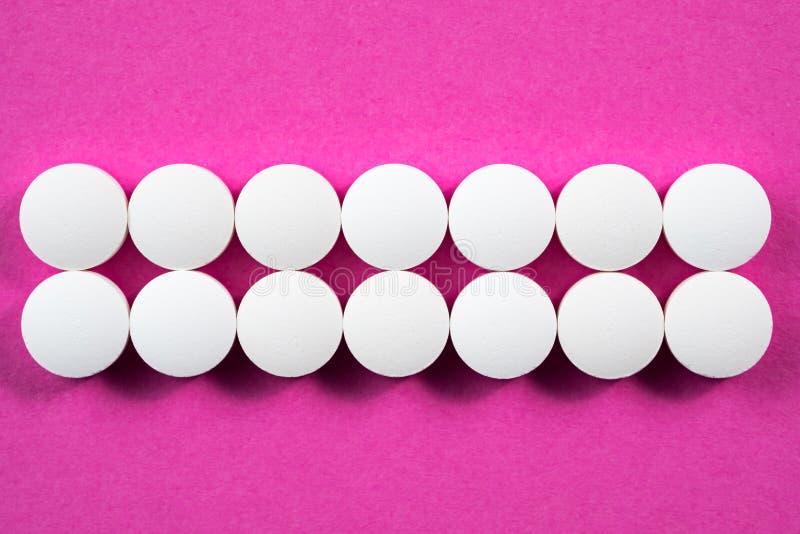 Pilules pharmaceutiques rondes blanches sur le fond rose image stock Pilules pharmaceutiques rondes blanches sur le fond rose image stock