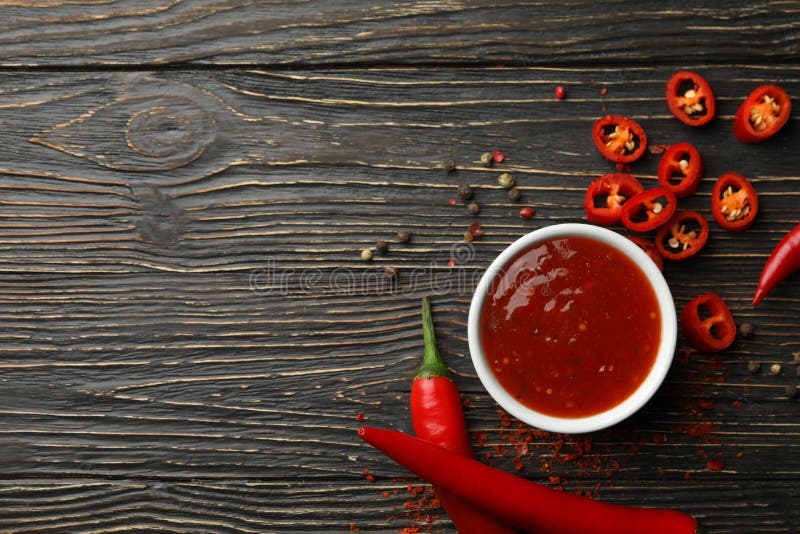 Chilli pepper and bowl of sauce on wooden  background, top view. Chilli pepper and bowl of sauce on wooden  background, top view