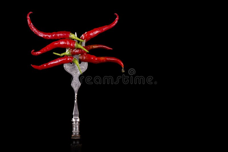 Pimentas em uma forquilha no fundo preto fotografia de stock Pimentas em uma forquilha no fundo preto fotografia de stock