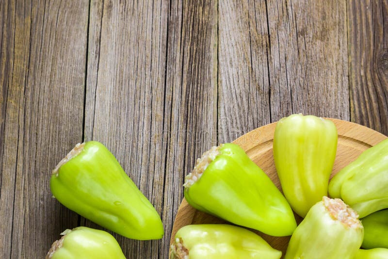 Pimientas crudas rellenas con la carne en una tabla de cortar de madera