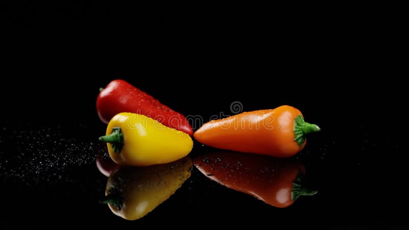 Pimientos amarillos naranja y rojo dulces colores vivos de vuelta en el fondo negro almacen de video