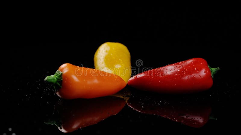 Pimientos amarillos naranja y rojo dulces colores vivos de vuelta en el fondo negro almacen de metraje de vídeo